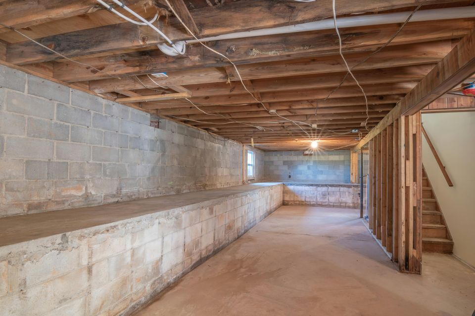 An unfinished Portland basement with cinder-block foundation walls and exposed joists, the typical starting point for interior waterproofing