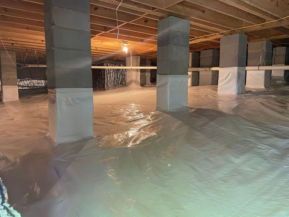 After replacement: closed-cell spray foam sealing the rim joists above a fresh reinforced vapor barrier in a Portland crawl space