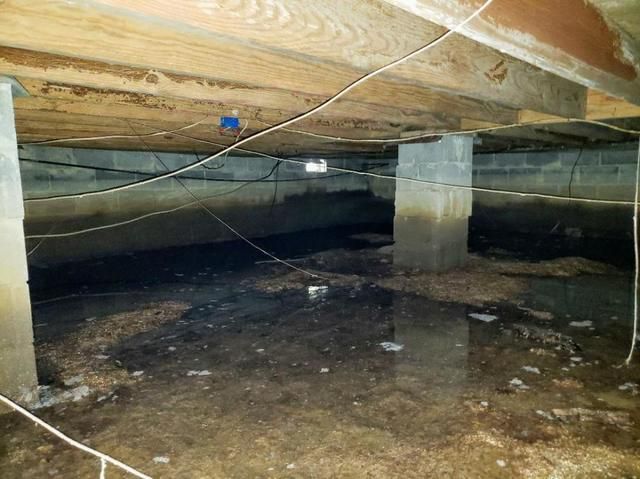 Sagging pink fiberglass batt insulation falling between floor joists in a Portland crawl space, the typical pre-replacement condition